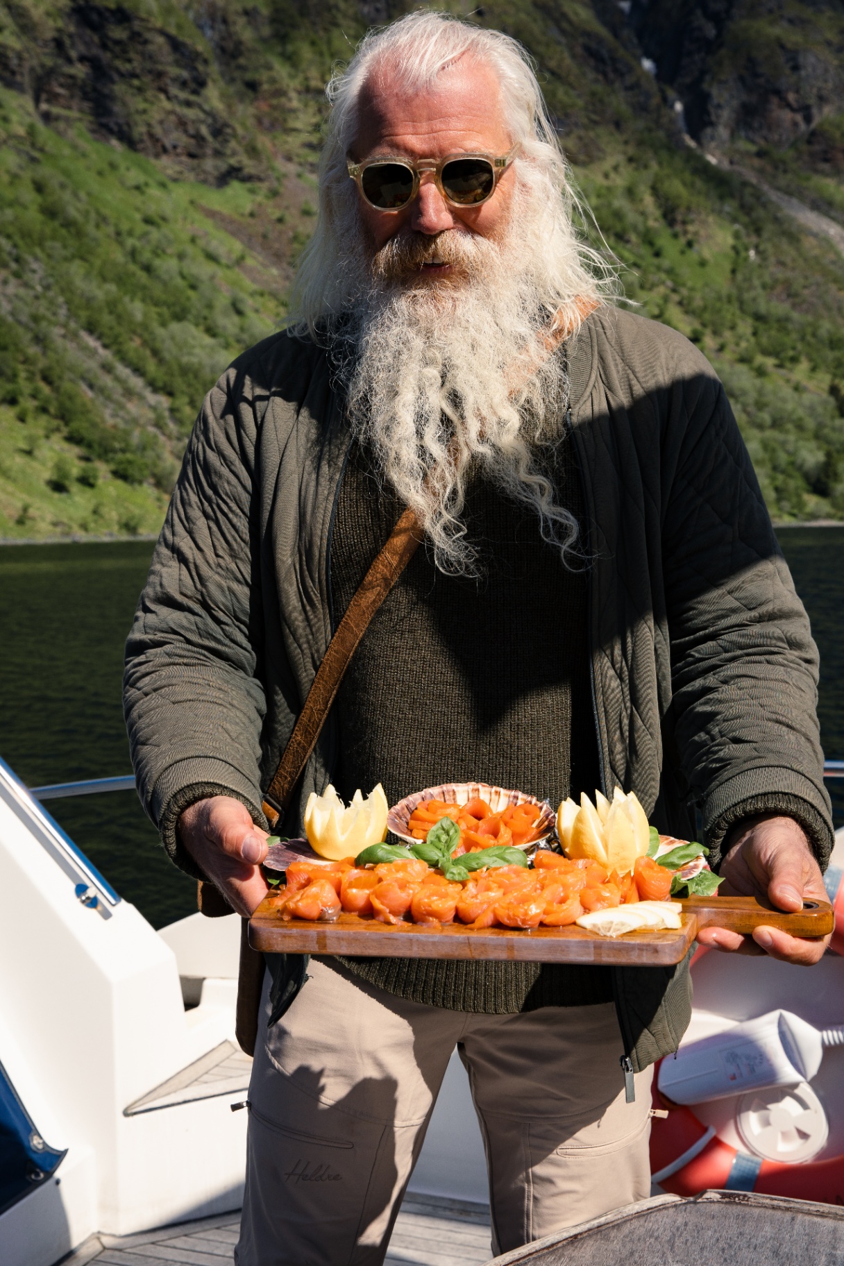 VISDI guide on a boat presenting a wooden board of fresh salmon sashimi