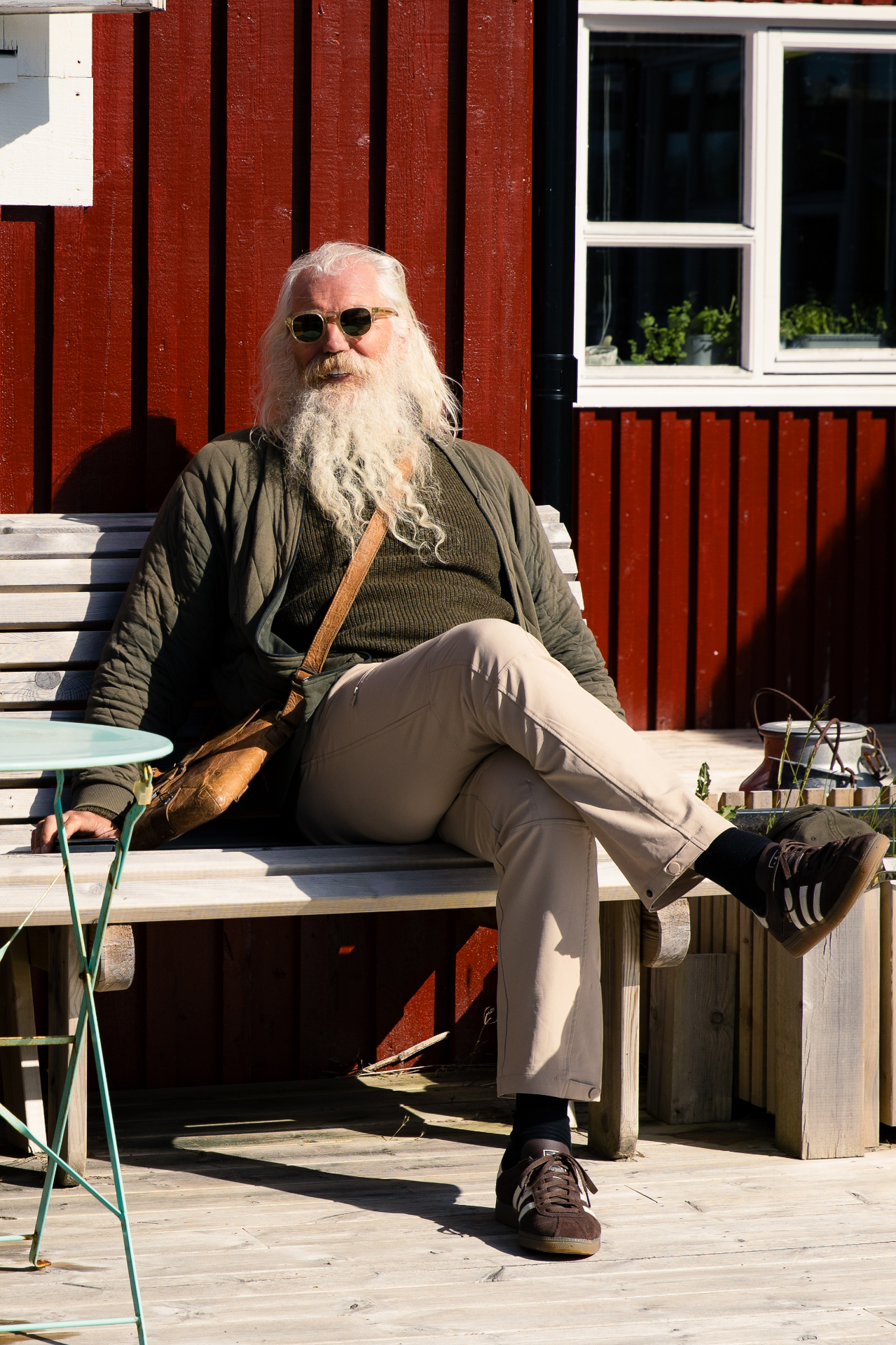 VISDI guide relaxing on a wooden bench outside a deep red cabin facade