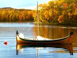 Traditional Nordland boat moored on a still lake with autumn-coloured forest reflected in the water