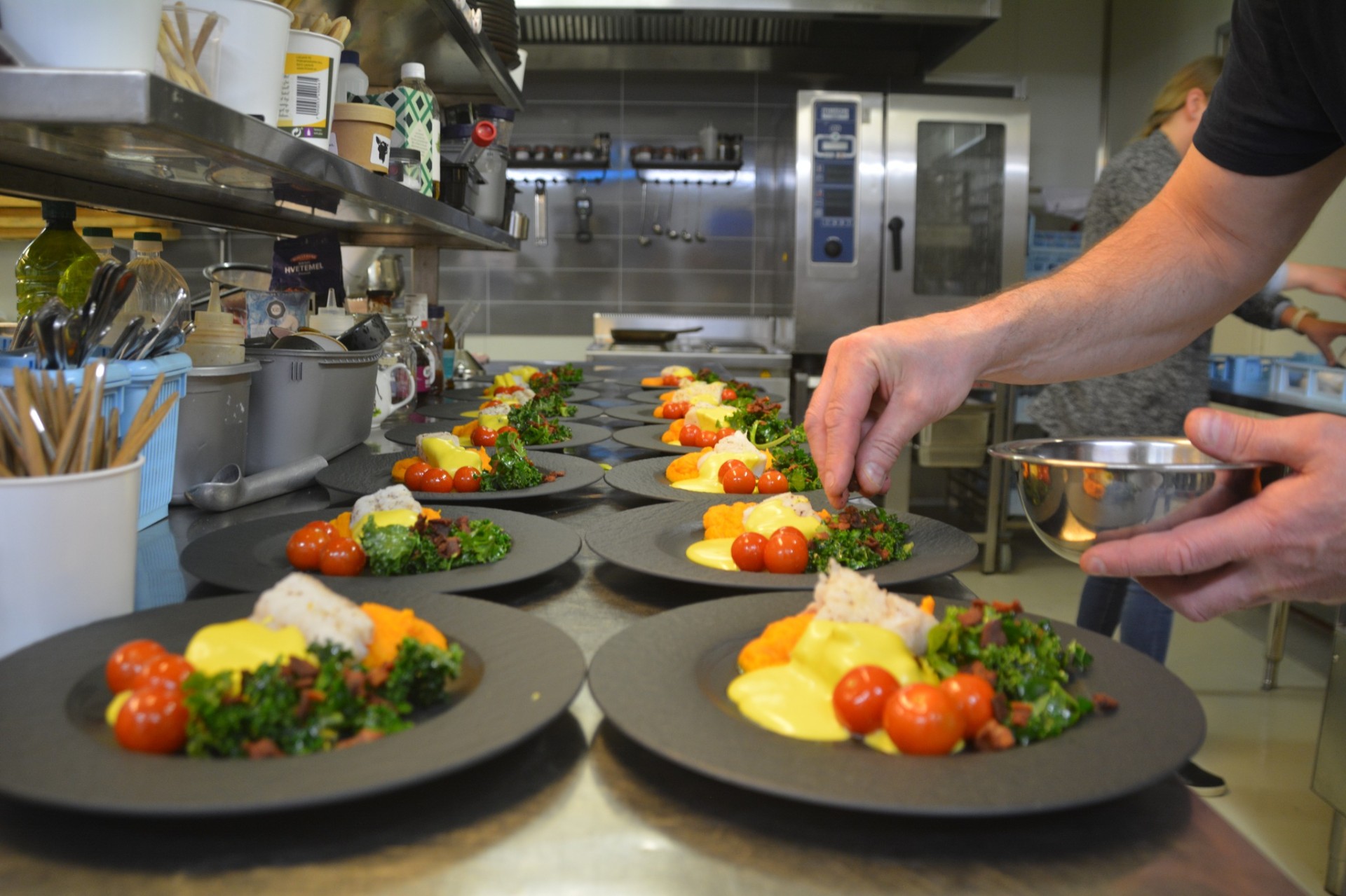 Chef finishing a row of plated courses in the kitchen before service
