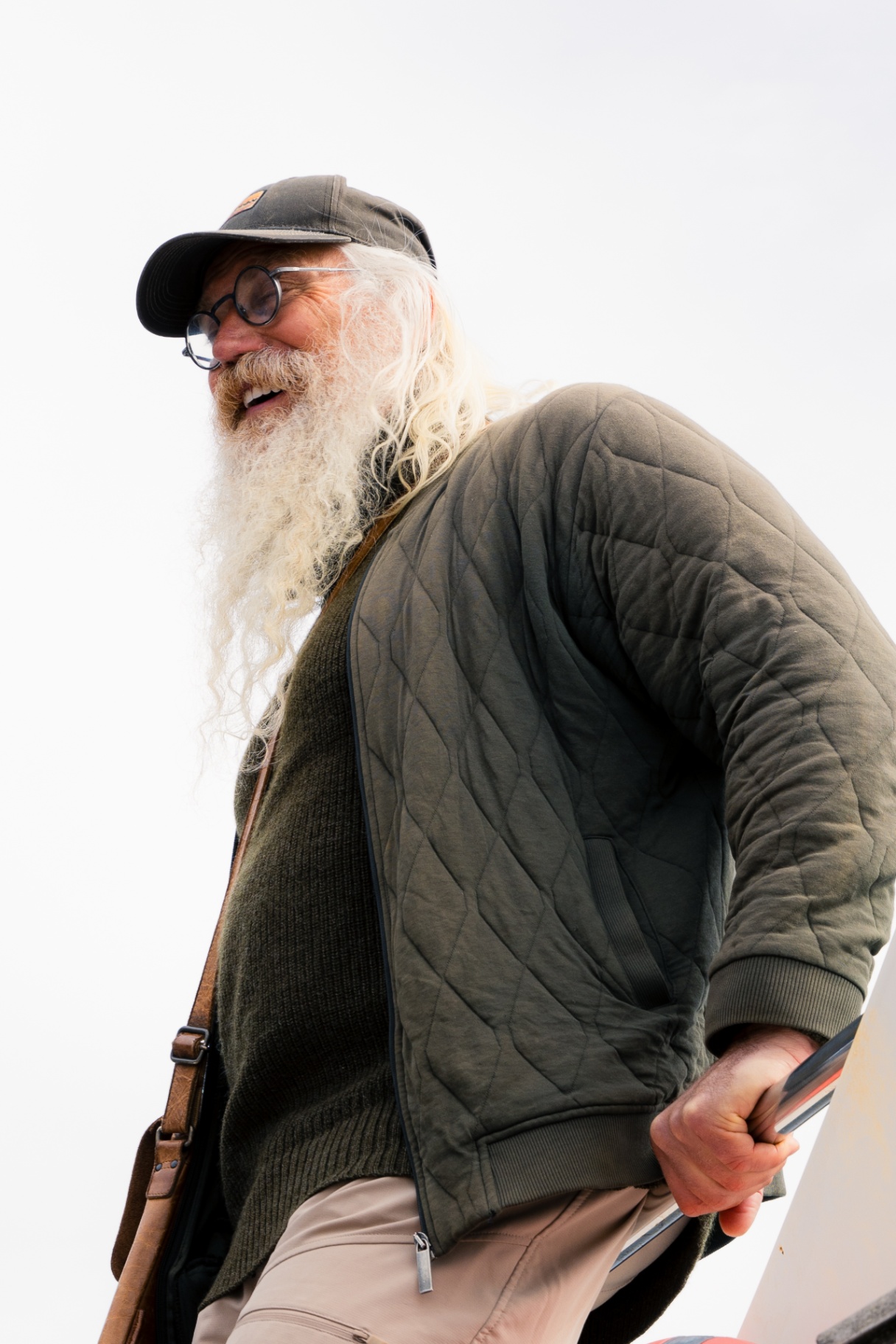 Portrait of a long-bearded VISDI guide in green quilted jacket against bright sky
