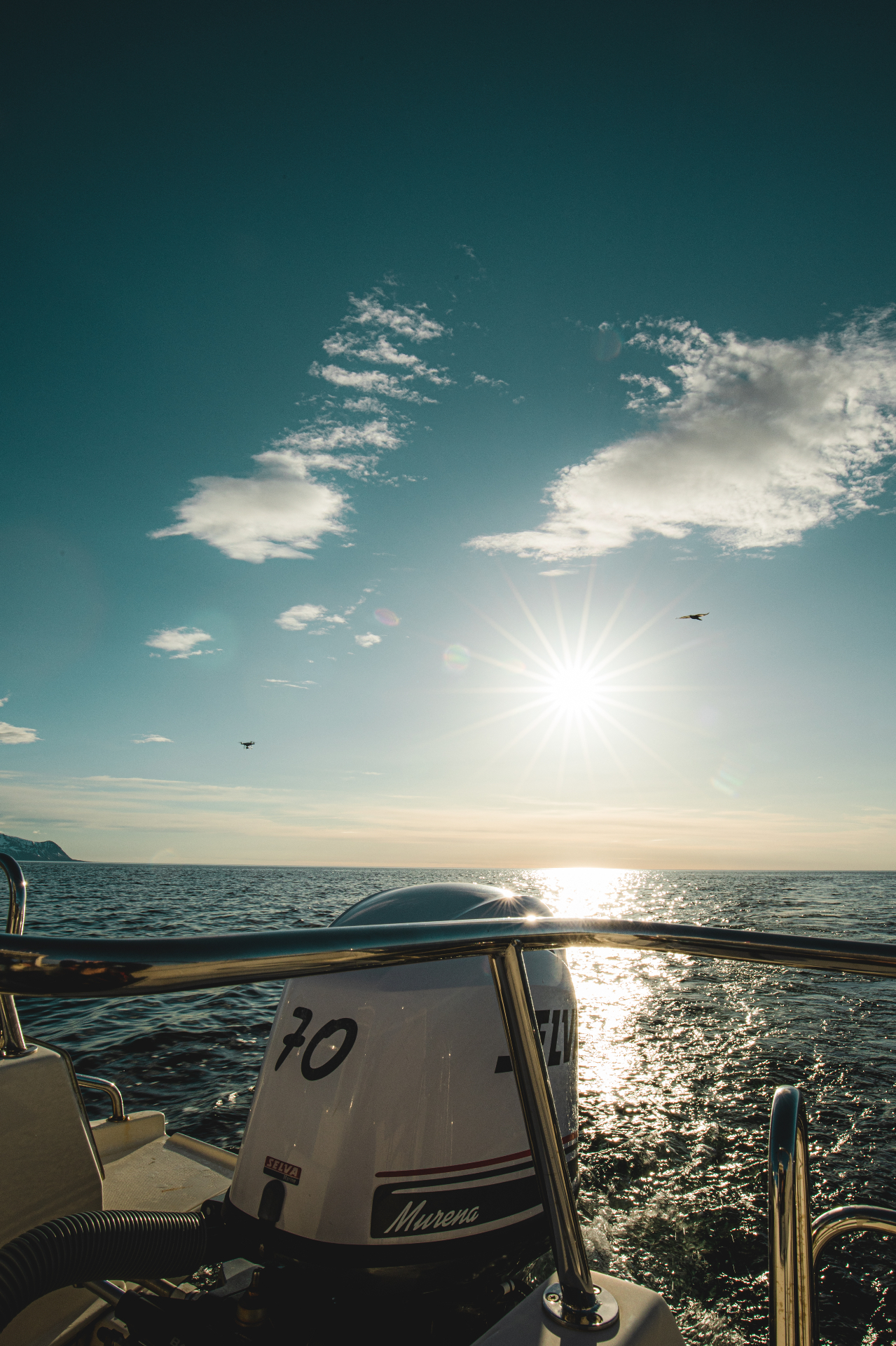 Sunburst over open Arctic sea seen from the stern of a small VISDI boat