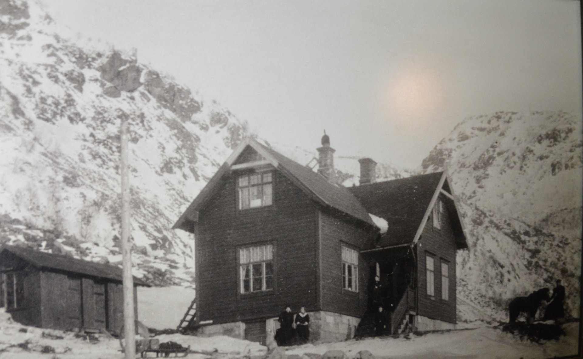 The Hornemann house in winter, with families standing outside beneath snow-covered mountains